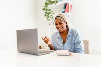 Black woman laughing during online meeting on laptop