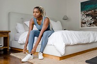 Black sporty woman tying shoelaces, getting ready for exercise