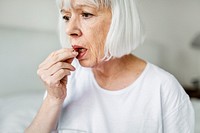 Depressed senior woman taking antidepressant, mental health image