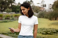 Woman texting on a phone in a park, casual wear