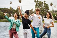 Diverse friends taking selfies by the lake, summer casual fashion