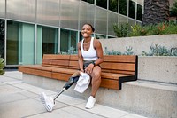 Woman with prosthetic leg carrying a towel sitting on the bench 