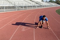 Asian man getting ready to take off on the running track