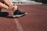 Man getting hurting his ankle and sitting on the track 