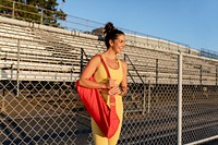 Woman in yoga top and leggings carrying a yoga mat 