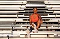 Woman athlete with prosthetic leg smiling carrying a towel and sitting to rest 