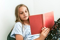 Young girl reading a book on a couch, new normal hobby