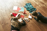 Kids writing Christmas cards on wooden floor