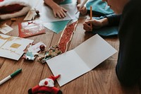 Kids writing Christmas cards on wooden floor