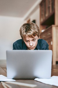 Boy using laptop on wooden floor, the new normal