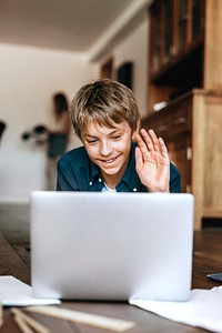 Boy using laptop on wooden floor, the new normal