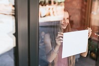 Young girl showing blank paper sign through glass window, the new normal