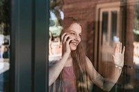 Young girl talking on the phone, hand touching glass window, the new normal