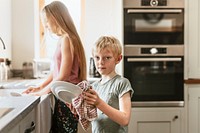 Young boy wiping dishes in kitchen, basic house chores