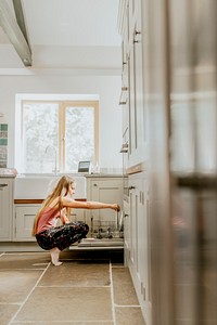 Blond girl unloading dishwasher, basic house chores