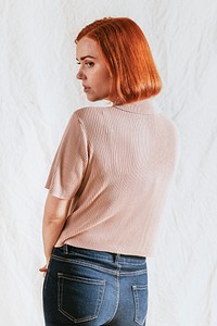 Woman in beige shirt standing alone, rear view