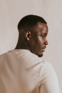 Black man in beige long sleeve, rear view