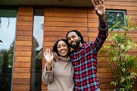 Happy couple waving outside house