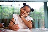 Happy girl doing homework in the kitchen