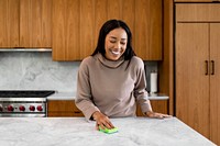 Woman polishing kitchen countertop with sponge