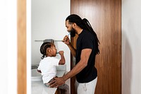 Boy learning to brush his teeth together with father