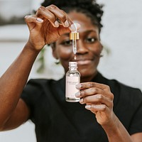 Dropper bottle mockup in African American woman’s hands psd