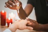 Woman using serum dropper on client's hand