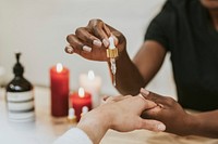 Woman using serum dropper on client's hand