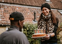 Woman bringing a birthday cake to her birthday friend 