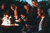 Friends enjoying s'mores and marshmellow together by the bonfire 