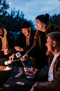 Friends enjoying s'mores and marshmellow together by the bonfire 