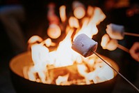 Friends enjoying s'mores and marshmellow together by the bonfire 