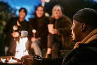 Friends enjoying s'mores and marshmellow together by the bonfire 