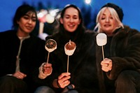 Friends enjoying s'mores and marshmellow together by the bonfire 