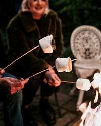 Friends enjoying s'mores and marshmellow together by the bonfire 