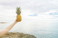 Someone holding a pineapple up in the air
