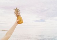 Someone holding a pineapple up in the air