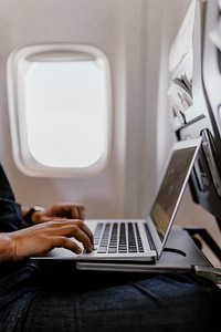 Man using a laptop on a plane. Visit <a href="https://kaboompics.com/" target="_blank">Kaboompics</a> for more free images.