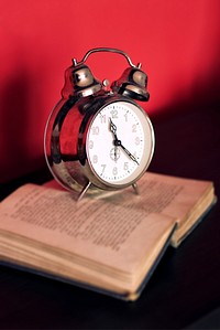Alarm clock on a book. Visit <a href="https://kaboompics.com/" target="_blank">Kaboompics</a> for more free images.