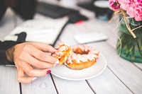 Woman eating a doughnut. Visit <a href="https://kaboompics.com/" target="_blank">Kaboompics</a> for more free images.