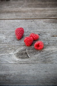 A few raspberries on a wooden surface