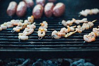 Shrimp in a barbeque tong on a grill
