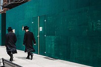 Orthodox Jewish men walking by a green wall