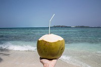 Woman holding a coconut at the beach