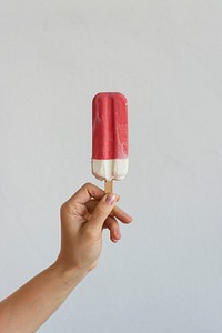 Hand holding a red and white popsicle