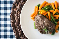 A beef steak with mini carrots and green beans