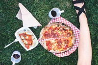 Woman eating salami pizza on the grass