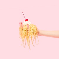 Woman holding freshly cooked spaghetti with whipped cream and cherry on top