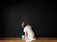 Little girl drawing on an empty black wall