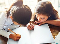 Girls writing and drawing on a white paper together copy space